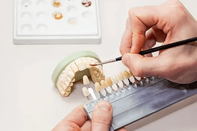Dental technician painting tooth model.