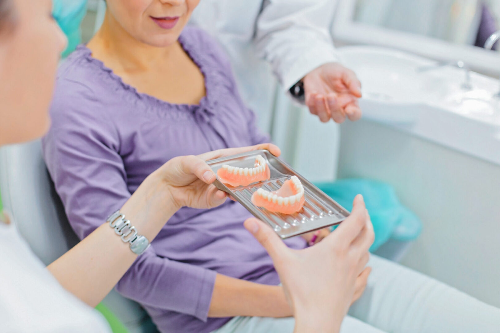 Dental patient examining dentures with dentist.